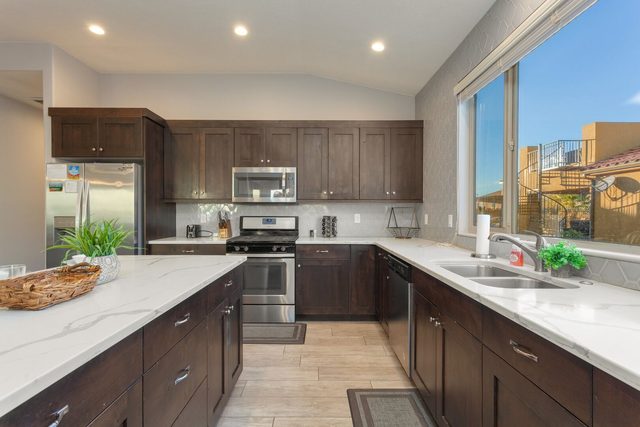 Kitchen with quartz counters, gas range and stainless refrigerator