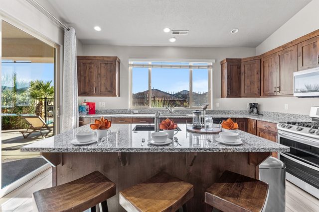 Granite kitchen island with three bar stools and window views