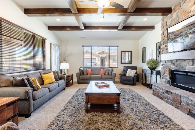 Living room sofas facing a stone fireplace with mounted TV