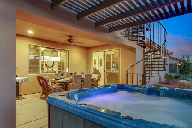 Private hot tub glowing beside the covered patio and spiral stairs