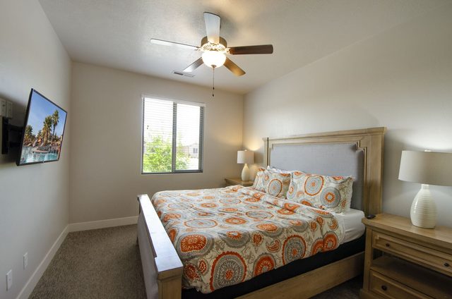 Bedroom with orange patterned bedding and upholstered headboard