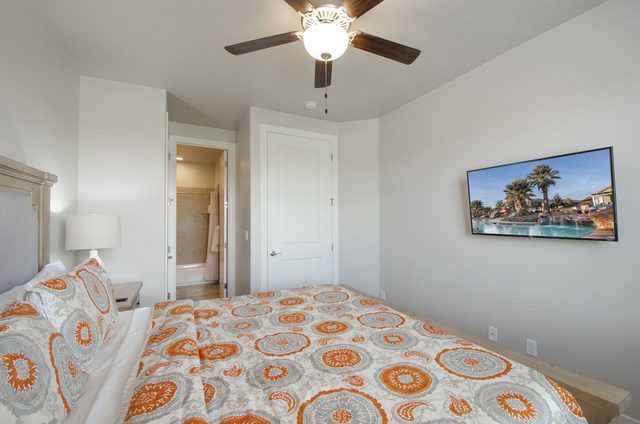 Bedroom with wall TV and doorway to the bathroom