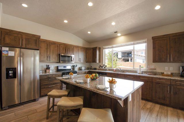 Kitchen with granite island, bar stools and stainless refrigerator
