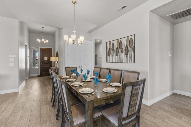 Dining table set for ten under a chandelier near the entry