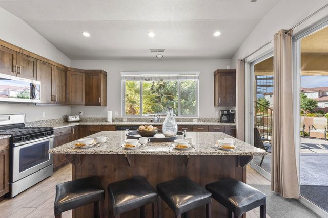 Kitchen with gas range, granite island and sliding patio door