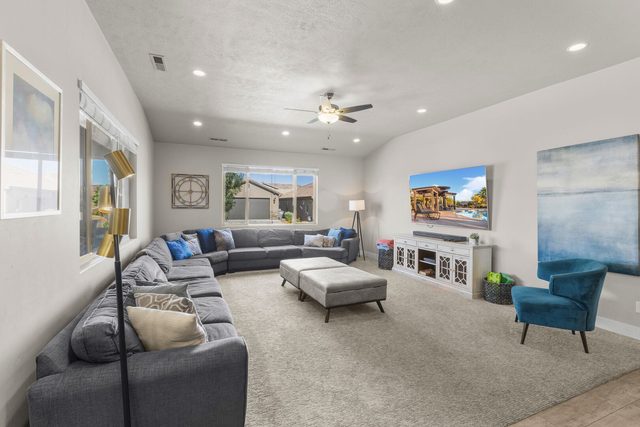 Living room with large gray sectional, ottoman and wall TV