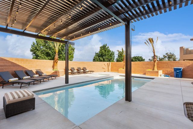 Private pool under a pergola with poolside lounge chairs