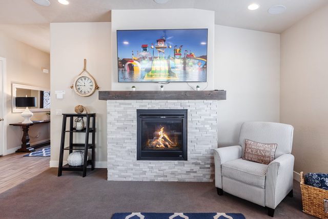 Stone fireplace with TV above and recliner at Paradise Village 28
