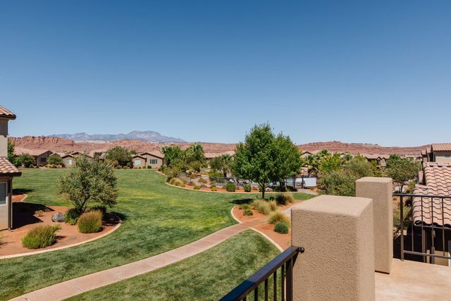 Balcony view over green lawn toward red cliffs at Paradise Village 36
