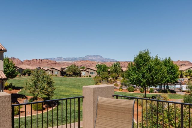 Balcony view of green lawn and distant red rock mesas