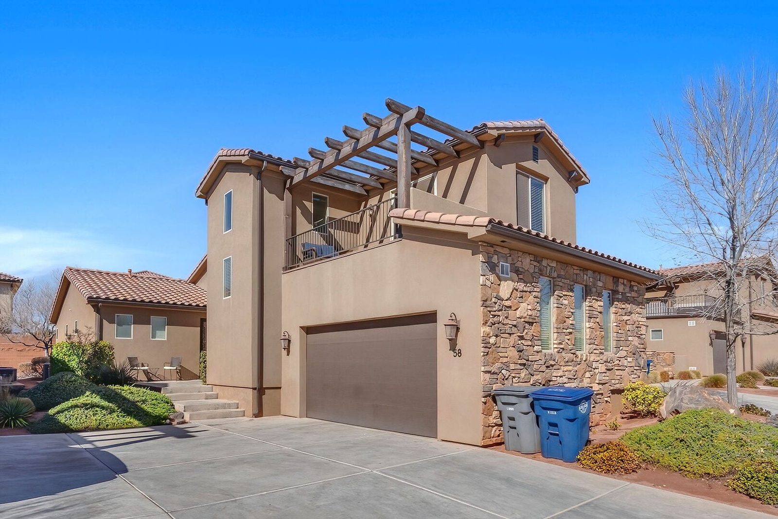 Two-story stucco and stone exterior of Paradise Village 58 with garage