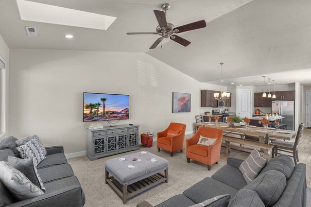 Living room with sofas, orange accent chairs and wall TV