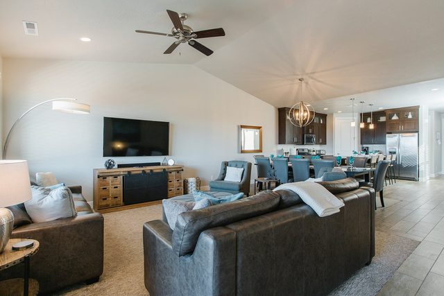Open living room with leather sectional and ceiling fan