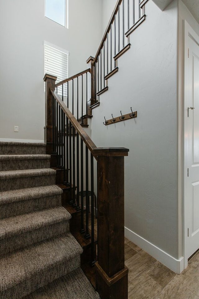 Carpeted staircase with wood railing to the upper floor