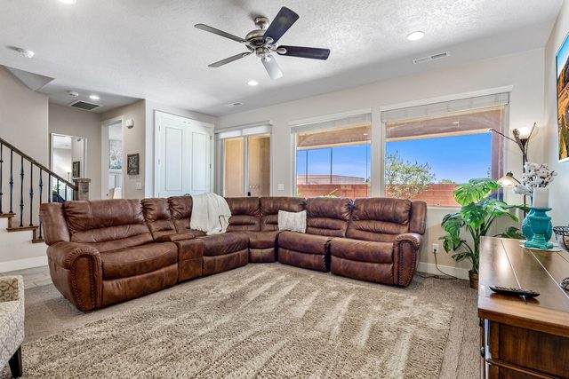 Large leather sectional under windows with staircase at left
