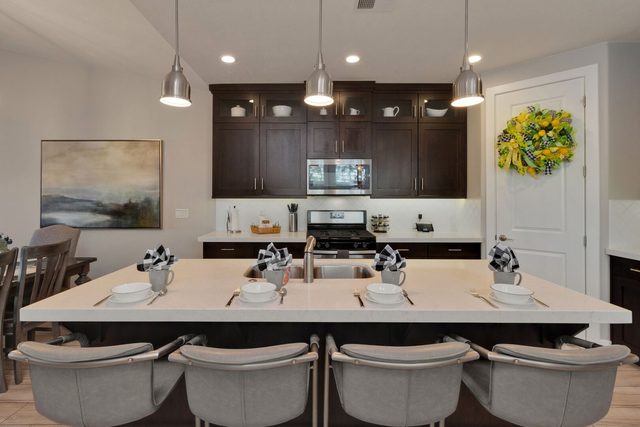 Kitchen island with four upholstered bar stools and pendant lights