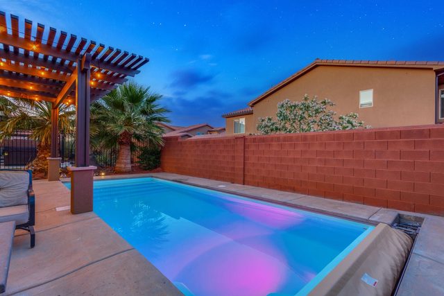 Private pool lit purple at night beside the patio