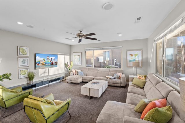 Living room seating facing wall TV with bright windows