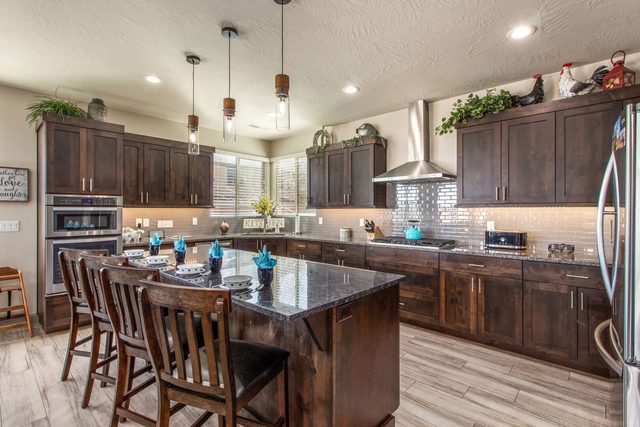 Kitchen island with bar seating, double ovens and dark wood cabinets
