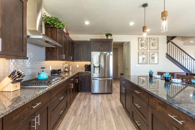 Galley kitchen with granite counters and stainless steel refrigerator