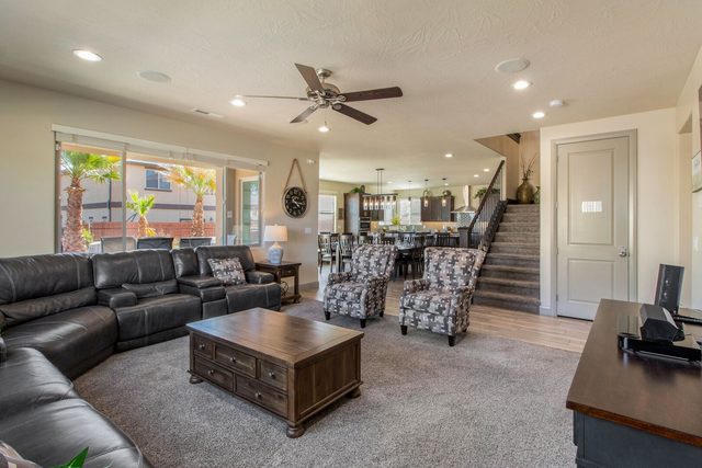 Open living room with leather sectional flowing into kitchen and stairs