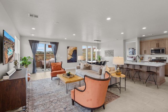 Living room with orange accent chairs and open kitchen at Paseos 1101