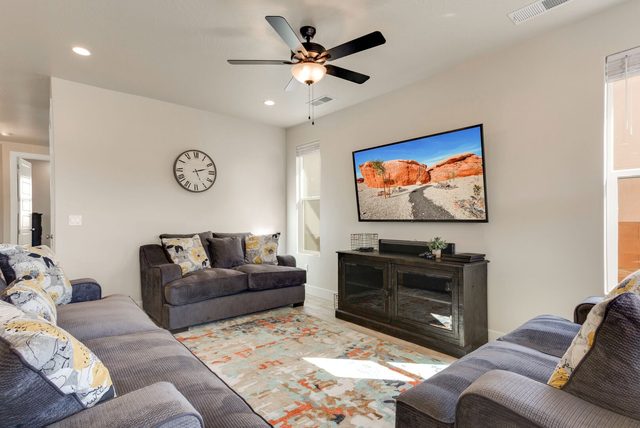 Main living room with three sofas and wall-mounted TV