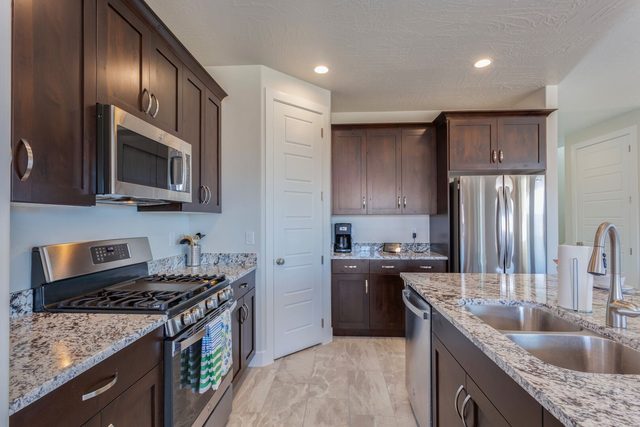 Kitchen with gas range, dark wood cabinets and granite counters