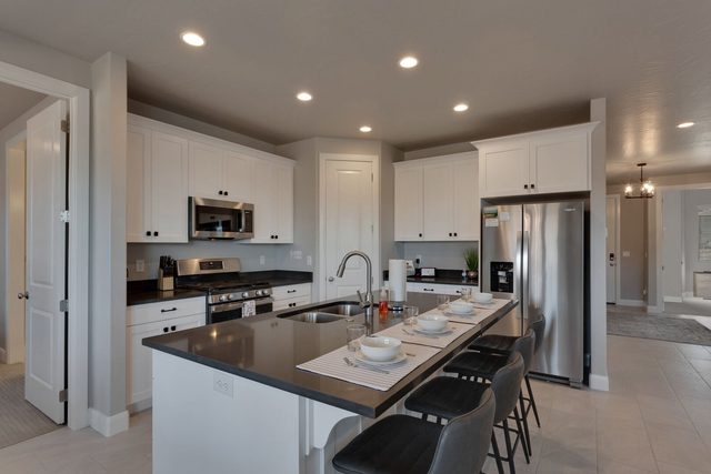 Kitchen with dark counters, white cabinets and island seating