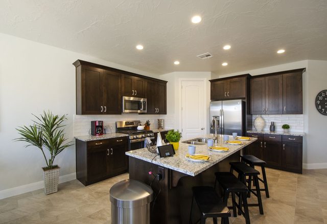Kitchen with dark cabinets, granite island and gas range