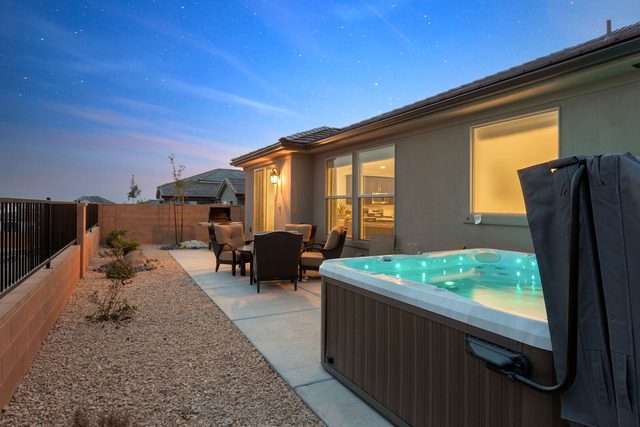 Private hot tub glowing at dusk beside the back patio