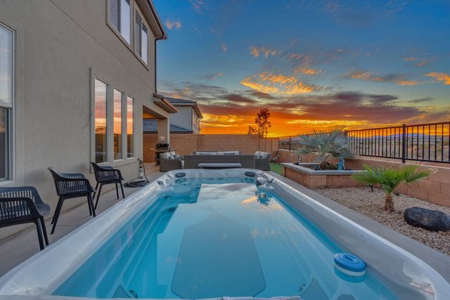 Swim spa with sunset sky over the backyard wall