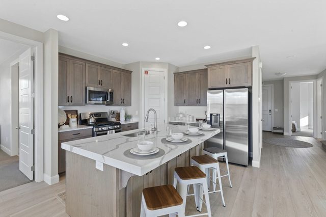 Kitchen island with quartz counter, bar stools and stainless fridge