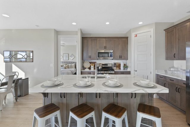 Kitchen island with four wooden-top stools and wood cabinets