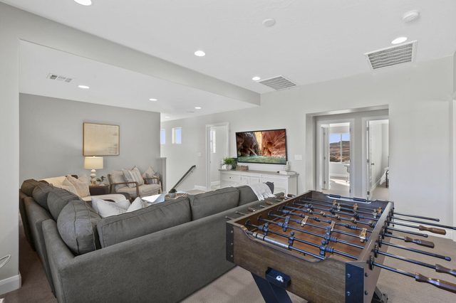 Upstairs loft with gray sectional sofa, wall TV and foosball table