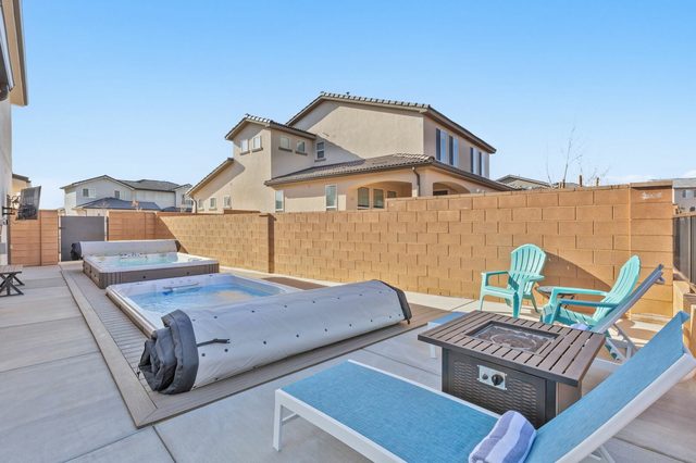 Swim spa with cover roll and fire table in the backyard