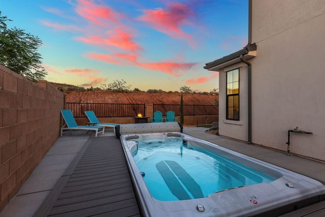 Swim spa with jets and loungers under a pink sunset sky