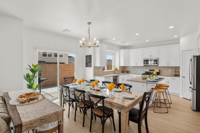Dining table with kitchen island and bar stools beyond
