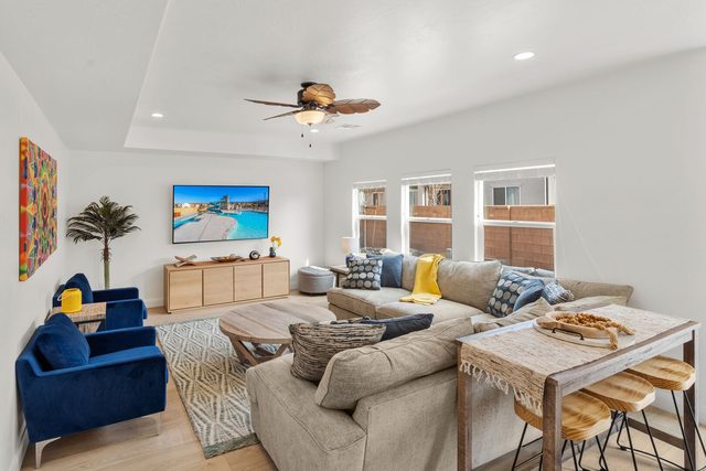 Living room with sectional, blue armchairs and wall TV