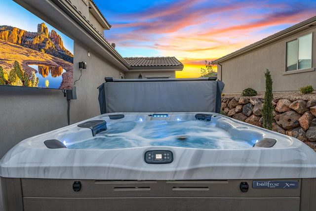 Lit private hot tub at dusk behind the home