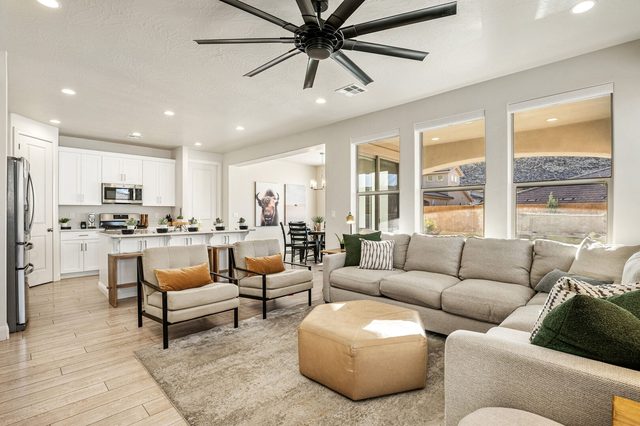 Open great room with sectional, armchairs and white kitchen
