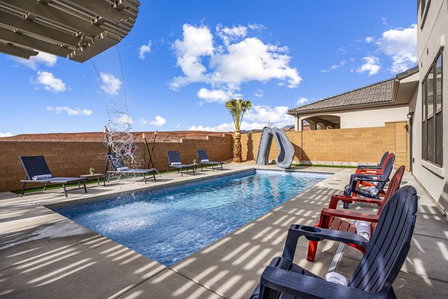 Private pool with water slide and red chairs at Paseos 1373