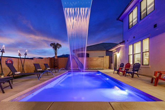 Pool waterfall feature lit purple at dusk at Paseos 1373