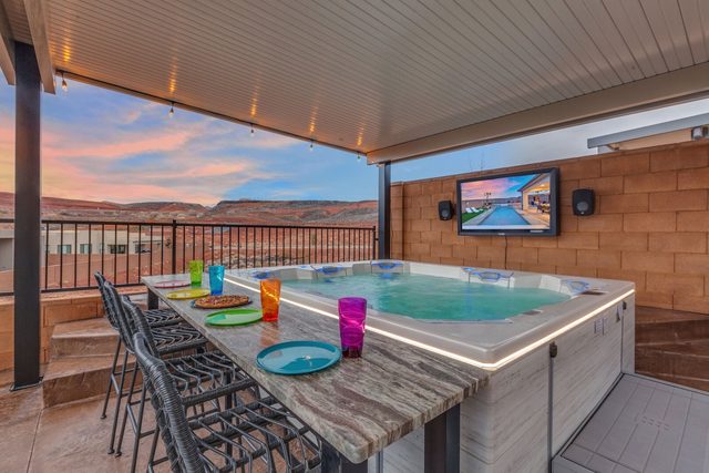 Hot tub under pergola with bar seating and outdoor TV