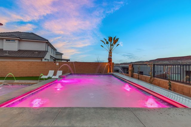 Private pool lit pink at dusk with fountain jets