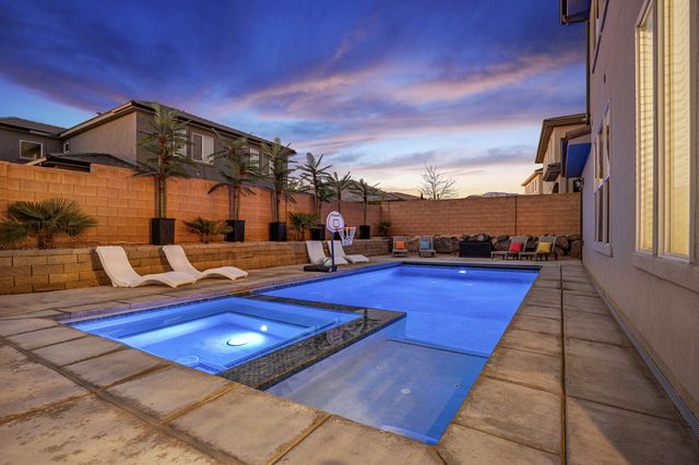 Lit private pool and spa at dusk with loungers