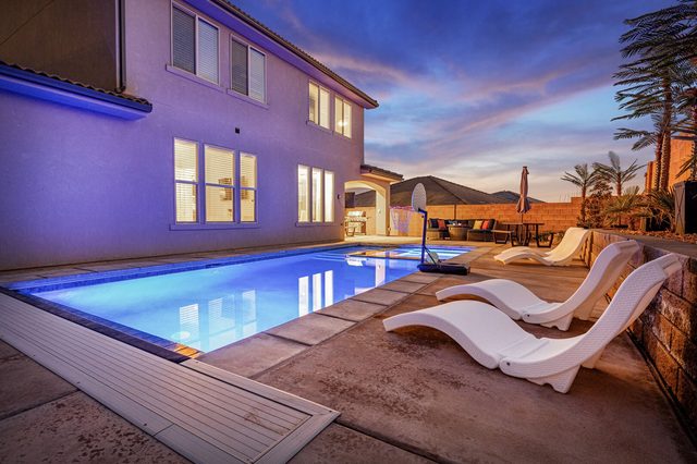 Private pool lit blue at night with lounge chairs