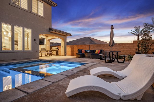 Hot tub and pool with loungers and patio at sunset