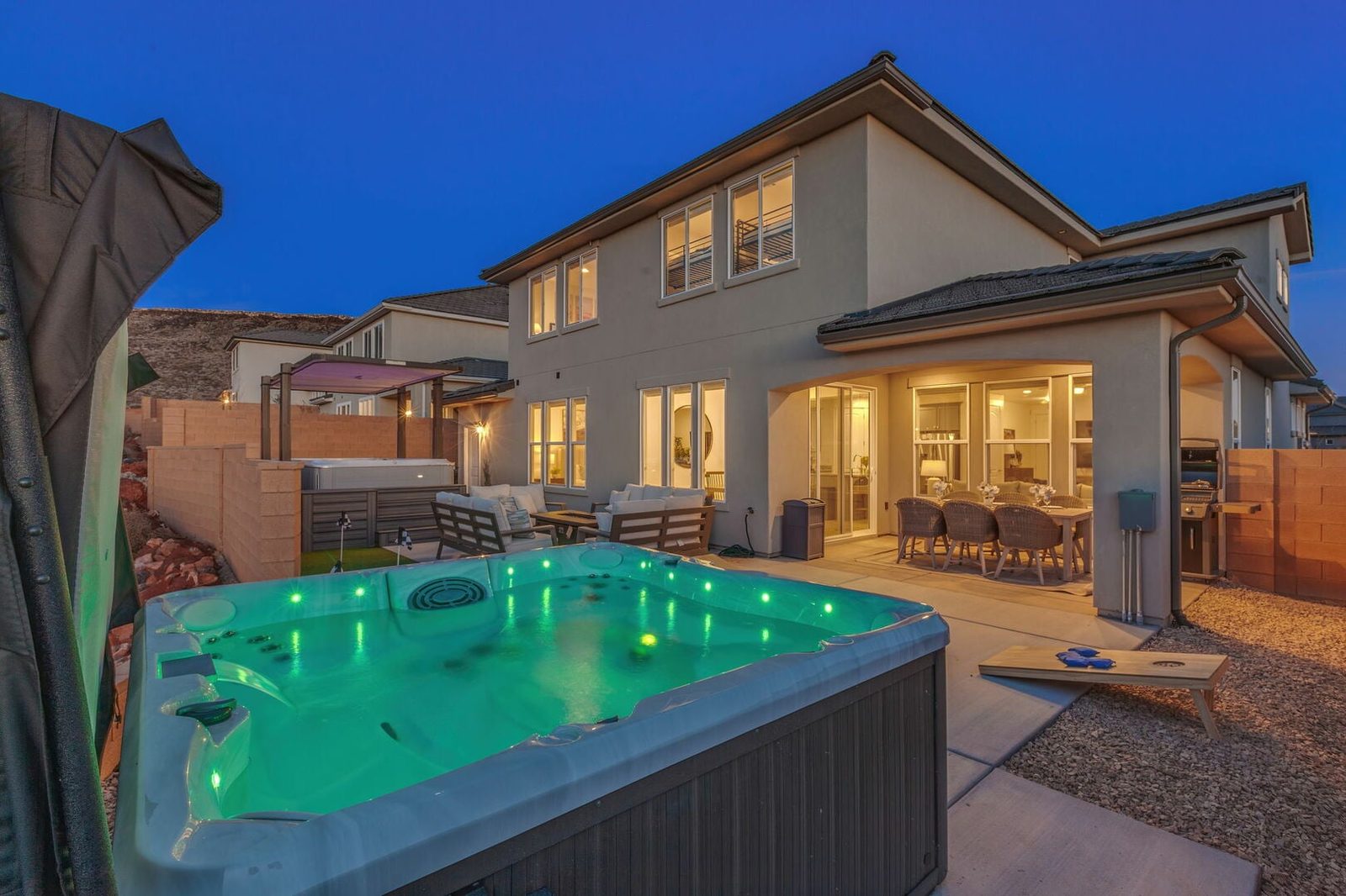 Illuminated swim spa beside the covered patio at dusk