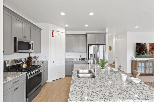 Kitchen with gas range, granite island and gray cabinetry